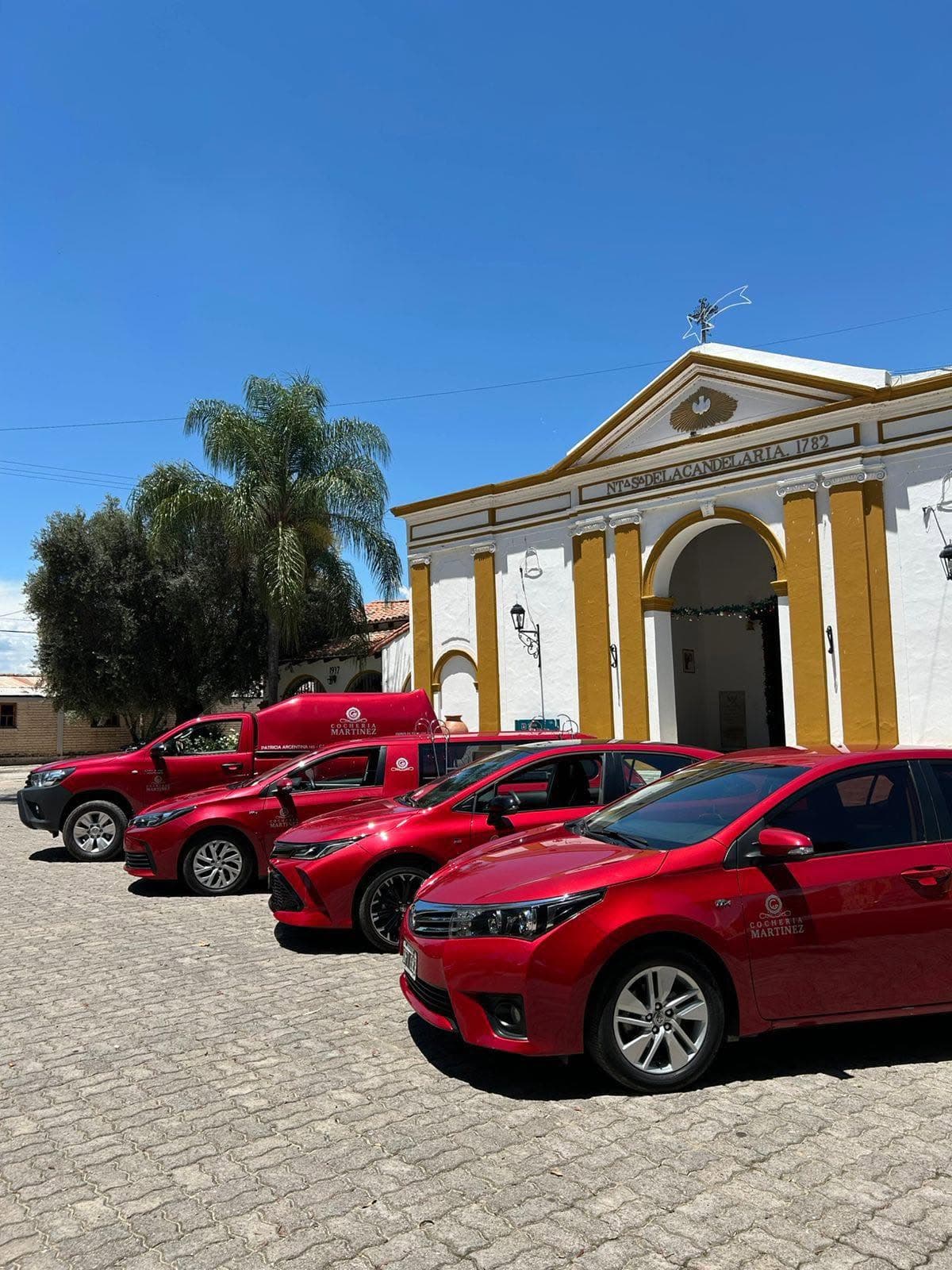 Flota de vehículos de Cochería Martínez frente a una iglesia histórica en General Güemes